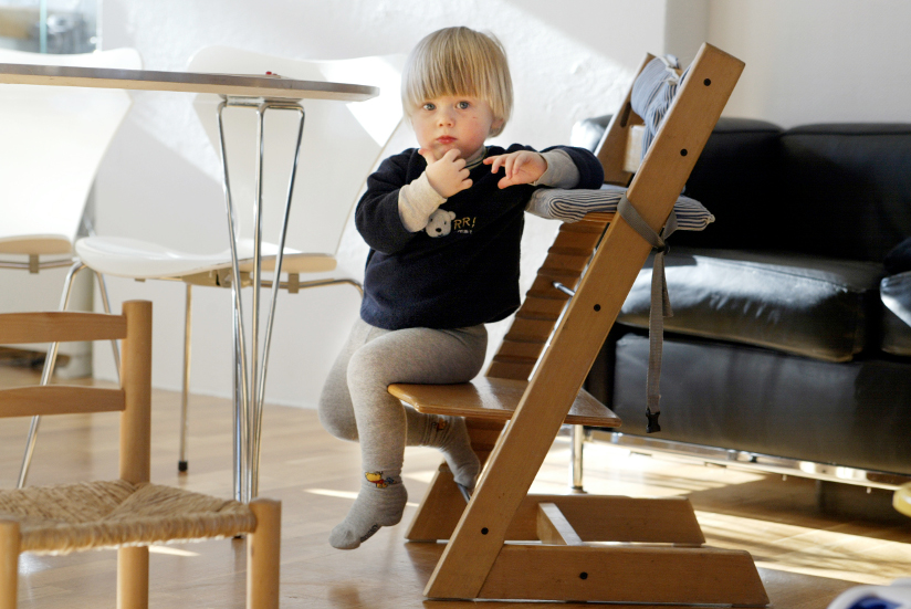 Fotografi av et lite barn som sitter på en «Tripp Trapp»-stol som er designet av Peter Opsvik. Barnet sitter på den nederste platen.