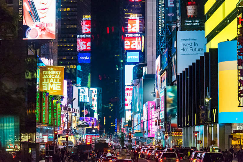 Fotografi av Times Square i New York om kvelden. Området er opplyst av neonreklame på bygningene.