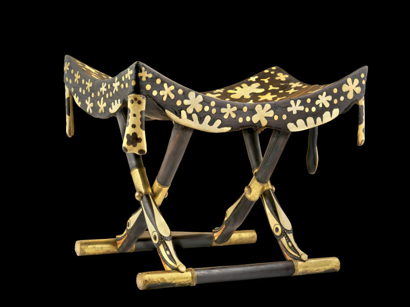 Fotografi av en egyptisk klappstol. Stolen er mørkebrun og dekorert med elfenben som er nedfelt i treverket.