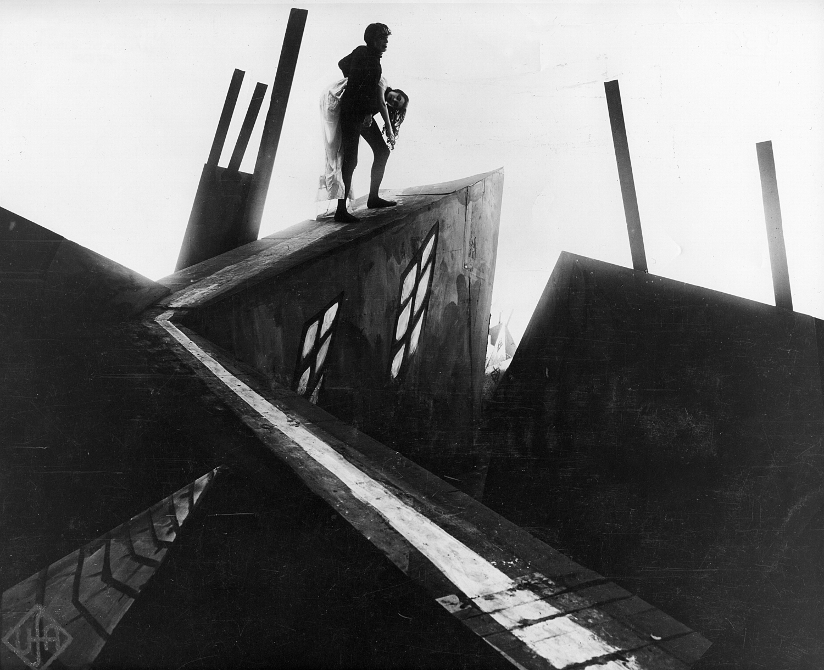 Svart-hvitt fotografi hentet fra den ekspresjonistiske stumfilmen <span class="italic">Doktor Caligaris kabinett</span> fra 1920. Fotografiet viser en mann som bærer en kvinne på et tak laget av kulisser.