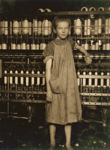 Svart-hvitt fotografi av en jente som arbeider ved et bomullspinner i Vermont i USA, ca 1910.
